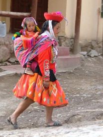 Die Kleidung einer
                            Indgena-Peruanerin mit Kind in Cusco, hier
                            ein Beispiel mit orangem Rock, rot-schwarzer
                            Jacke, und Tuch in Blau, Violett und Rot
                            wowie mit roter Kopfbedeckung mit weissem
                            Band