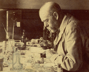 Robert Koch mit Mikroskop im Hintergrund,
                        1880 ca.