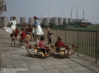Kinderkrippe in der DDR mit Gerten neben
                        einem Kohlekraftwerk in Vetschau