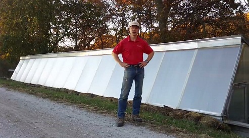 Farmer at his pit greenhouse in front
              of the solar window front