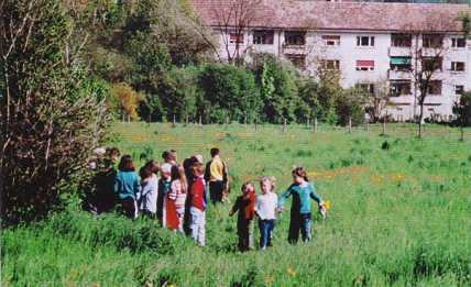 Auenpark: Kindergruppe, Wohnhaus im
                            Hintergrund.