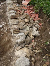 Muro seco en una pendiente en
                            construcción también con tiestos en la fila
                            interior