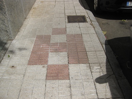 Trottoir / B�rgersteig
                        in weissen, gerillten Platten mit Mustern in
                        roten, gerillten Platten