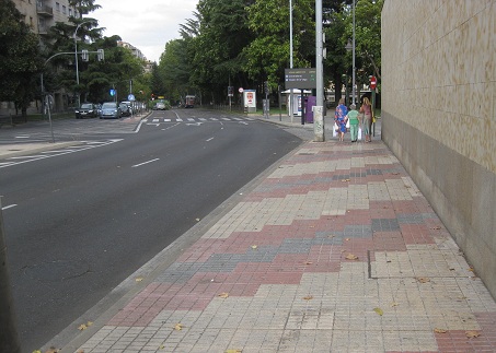 Trottoir / B�rgersteig in
                        gerillten, weissen Platten mit diagonalen
                        B�ndern in rot-schwarz