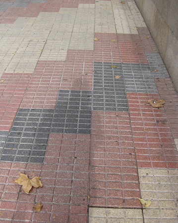 Trottoir / Bürgersteig in gerillten,
weissen Platten mit diagonalen Bändern in
rot-schwarz, Zoom Trottoir / Bürgersteig
in gerillten, weissen Platten mit diagonalen
Bändern in rot-schwarz, Zoom