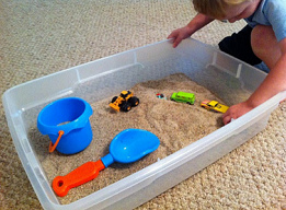 Cajn de arena en la casa 02 con
                              arena, coches de juguetes y una excavadora
                              de juguete, con una pala.