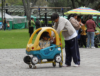 Un ni�o de 2 a 5 a�os manejando su
                              primer auto / coche empujado por una
                              persona grande, en el parque Ejido en
                              Quito en Ecuador